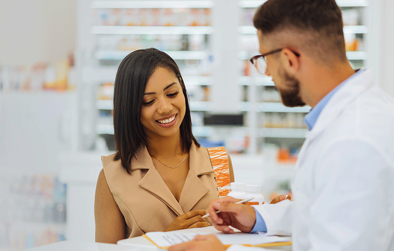 Male pharmacist talking to a female customer while viewing paperwork
