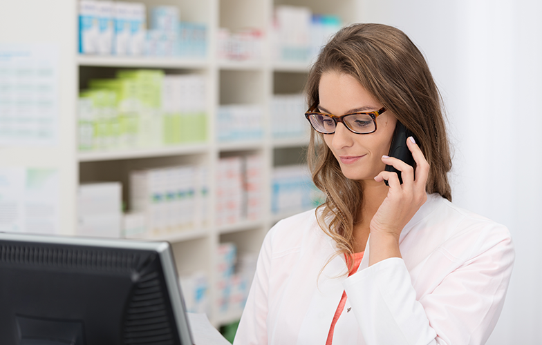Pharmacist talking on the phone while looking at a computer screen