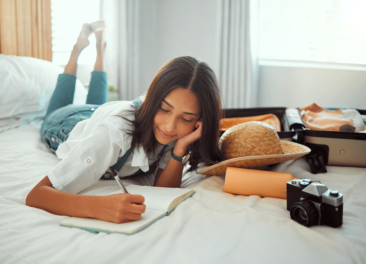 Girl lying on bed writing in a journal
